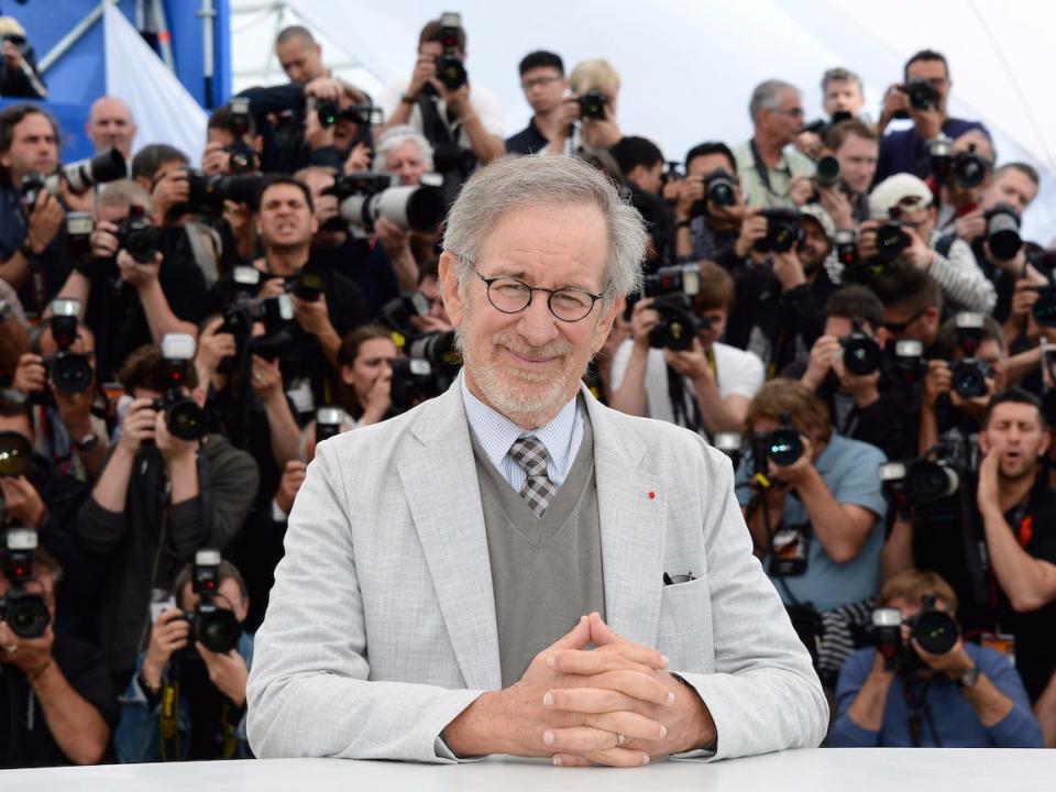 Steven Spielberg sits in front of photographers