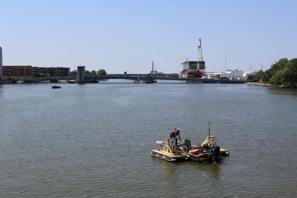 Tetra Tech employees pick up a water turbidity monitor in July 2020 near the Ray Nitschke Memorial Bridge in downtown Green Bay. Cleanup of PCBs in the Fox River has wrapped up, but monitoring will continue for years.