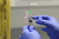 FILE - In this Wednesday, Aug. 5, 2020 file photo, senior Clinical Research Nurse Ajithkumar Sukumaran prepares the COVID-19 vaccine to administer to a volunteer, at a clinic in London. U.K. researchers said Tuesday Oct. 20, 2020, they are preparing to begin a controversial experiment that will infect healthy volunteers with the new coronavirus to study the disease in hopes of speeding up development of a vaccine. (AP Photo/Kirsty Wigglesworth, File)