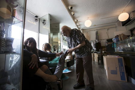 Owner Arturo Azinian helps a customer in his shoe repair shop in Beverly Hills, California April 24, 2015. Picture taken April 24, 2015. REUTERS/Mario Anzuoni