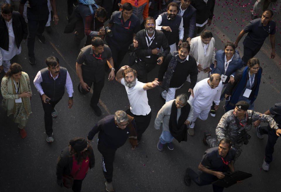 Rahul Gandhi, leader of India's opposition Congress party, centre in white T-shirt, throws flower petals towards press photographers during a march, in New Delhi, India, Saturday, Dec. 24, 2022. Rahul Gandhi, leader of India's beleaguered opposition Congress party, on Saturday marched in New Delhi along with his supporters, part of his five-month-long 3,570km (2,218-mile) countrywide trek through 12 states that began 105 days ago.(AP Photo/Altaf Qadri)