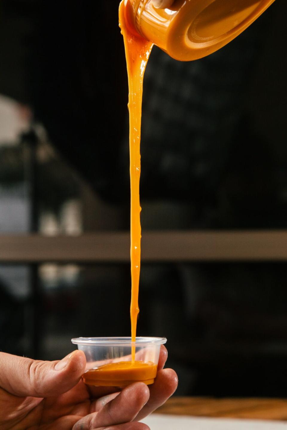 Barbecue sauce is poured into a plastic container