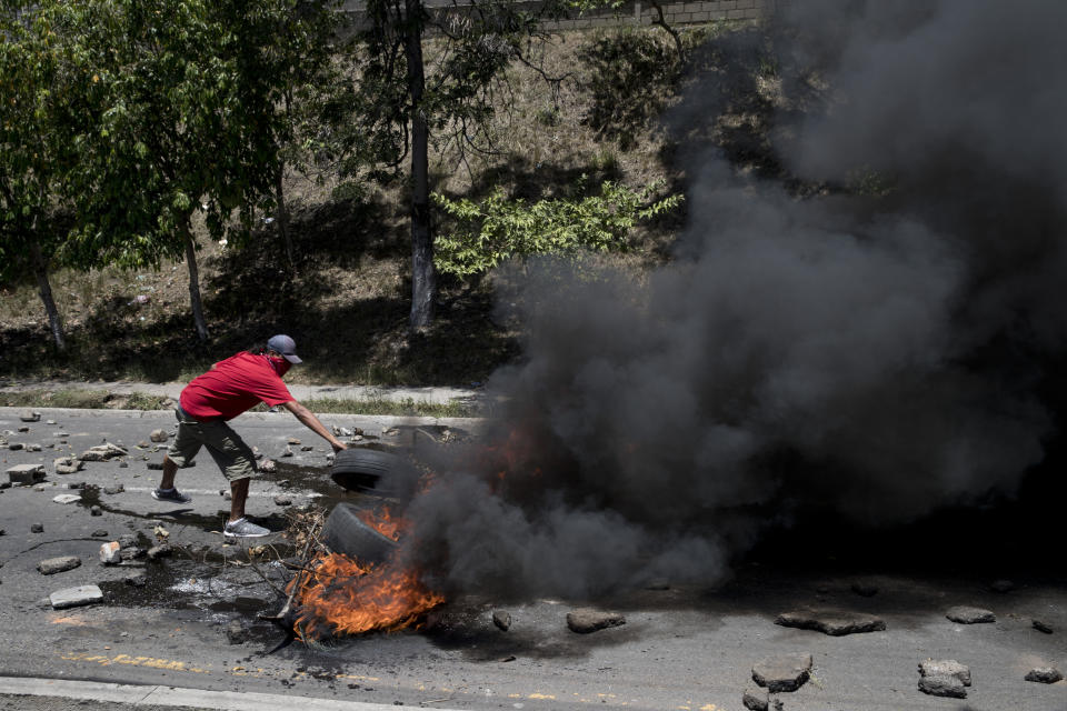 A man blocks a road with burning tires to protest Honduras' President Juan Orlando Hernandez in Tegucigalpa, Honduras, Friday, Aug. 23, 2019. Hernández has suffered a credibility crisis since the Supreme Court cleared the way for his re-election despite a constitutional ban, and his subsequent 2017 election win was marred by irregularities. (AP Photo/Eduardo Verdugo)