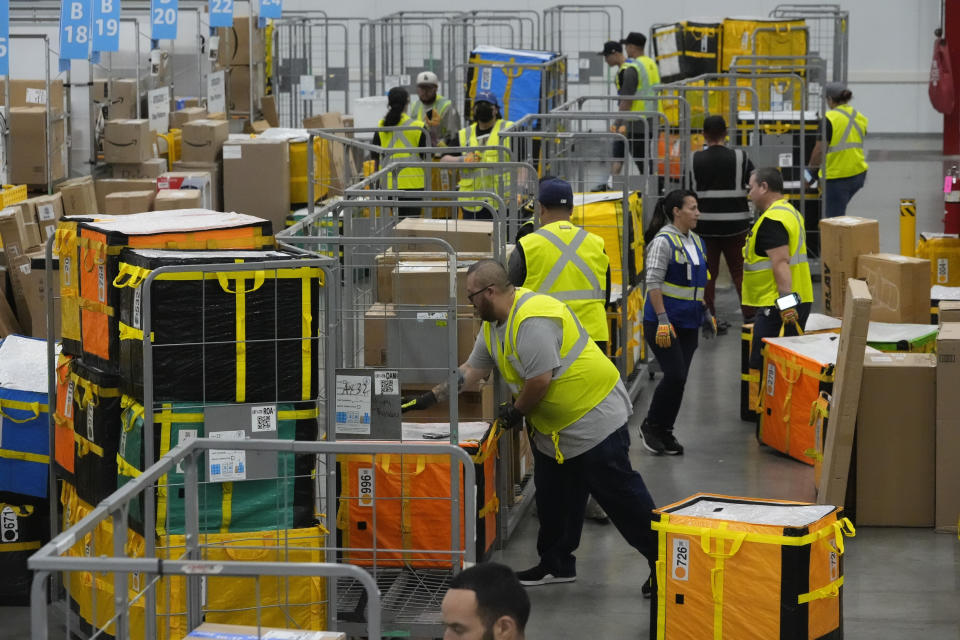 FILE - Amazon employees load packages on carts before being put on to trucks for distribution to customers for Amazon's annual Prime Day event at an Amazon's DAX7 delivery station on July 16, 2024, in South Gate, Calif. (AP Photo/Richard Vogel, File)