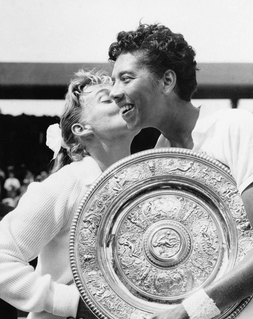 FILE - In this July 6, 1957 file photo, Althea Gibson of New York city, holding the large gold plate presented to her as the winner of the Women's Singles Tennis title at the All England Lawn Tennis Championships in Wimbledon, London, is kissed by her opponent, Darlene Hard. Gibson became the first black player, male or female, to win Wimbledon when she defeated fellow American Hard in the final. She ended up with five Grand Slam singles titles, including two Wimbledon crowns, and was twice named The Associated Press’ “Female Athlete of the Year.” Her pioneering didn’t end with tennis. In 1964, Gibson became the first black woman to play in the Ladies Professional Golf Association. (AP Photo, File)