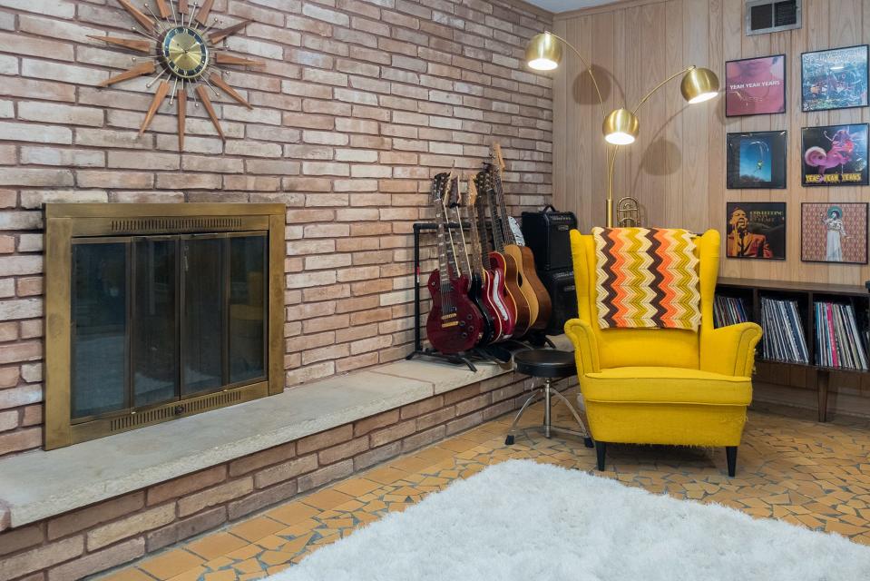 The den features the original brick that surrounds the fireplace.  This room is often referred to as the music room, with a rack full of guitars and a storage unit featuring a vinyl record collection and a turntable.