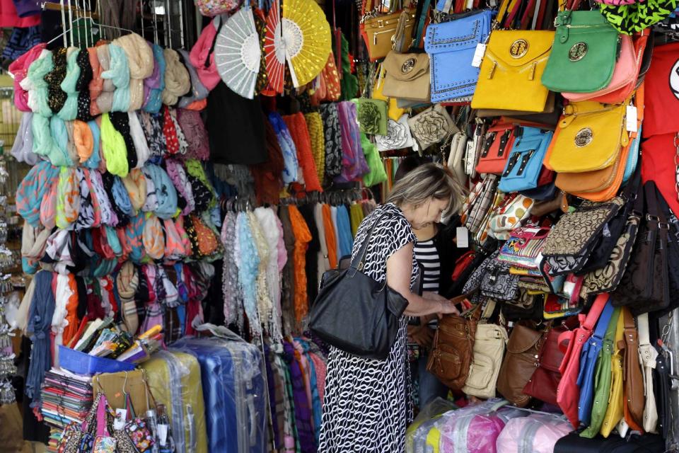 A woman looks through a display of purses on Canal Street in New York, Tuesday, June 4, 2013. Bargain hunters from around the world flock to Manhattan's Chinatown for legally sold bags, jewelry and other accessories bursting onto sidewalks from storefronts along Canal Street. (AP Photo/Seth Wenig)