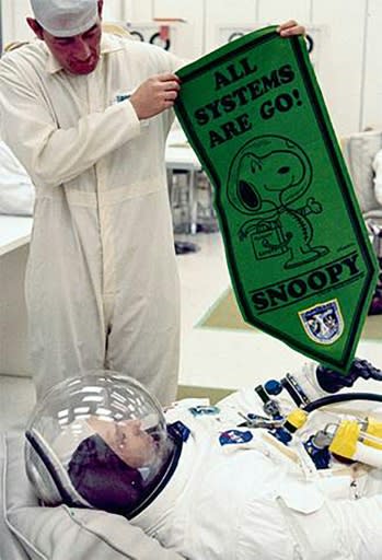 In this May 1969 image obtained from NASA, astronaut Tom Stafford, wearing his spacesuit, is being shown a pennant bearing the Peanuts comic book character Snoopy at the Kennedy Space Center in Florida