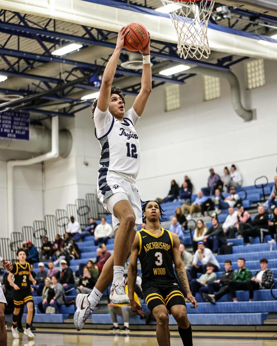 Jaitavius Kelly (12) skies past Milan Dean (3) to slam the ball through the hoop. The Chambersburg Trojans played the Archbishop Wood Vikings in the PIAA Class 6A playoffs on Wednesday, March 15, 2023. The Vikings defeated the Trojans, 72-45.