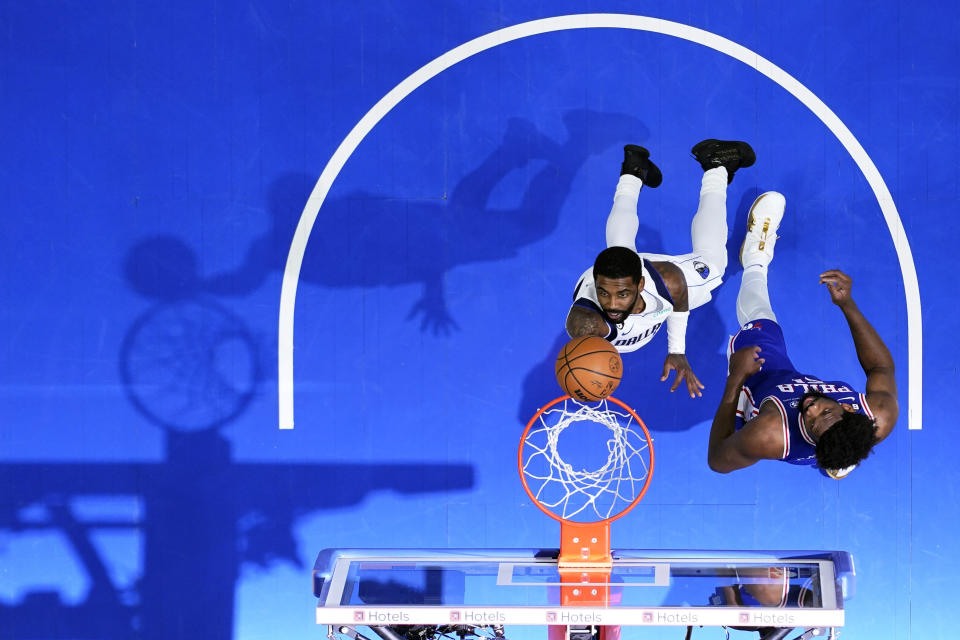 Dallas Mavericks' Kyrie Irving, left, goes up for a shot against Philadelphia 76ers' Joel Embiid during the second half of an NBA basketball game, Wednesday, March 29, 2023, in Philadelphia. (AP Photo/Matt Slocum)