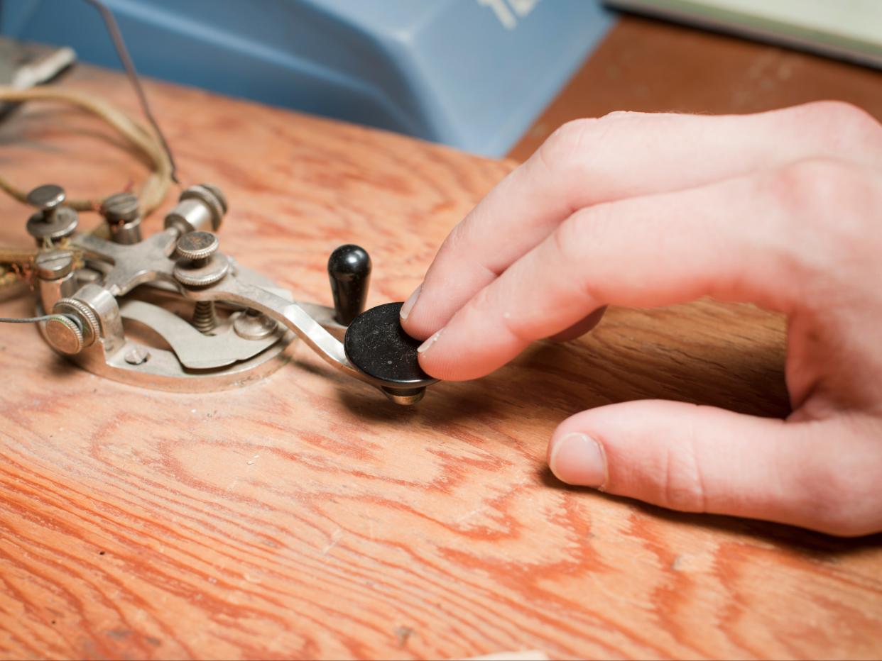 A man works a telegraph key at a desk. (Getty Images)