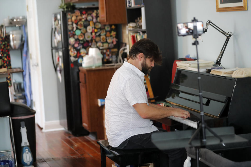 Andre Bohren plays a classical piano composition by Frédéric Chopin from his living room, as he livestreams it to WWOZ radio in New Orleans, Wednesday, April 29, 2020. With New Orleans music venues shuttered for more than a month now because of the coronavirus outbreak, musicians and fans are finding new places to connect – porches, living rooms, studios and lawns – and reaching their largest audiences online, many streaming performances live on social media platforms. But for the city's club owners awaiting the green light to reopen there's concern about all the uncertainties, like how long it may take tourists to return, how soon the music scene will rebound and when it does, what it will look like. (AP Photo/Gerald Herbert)