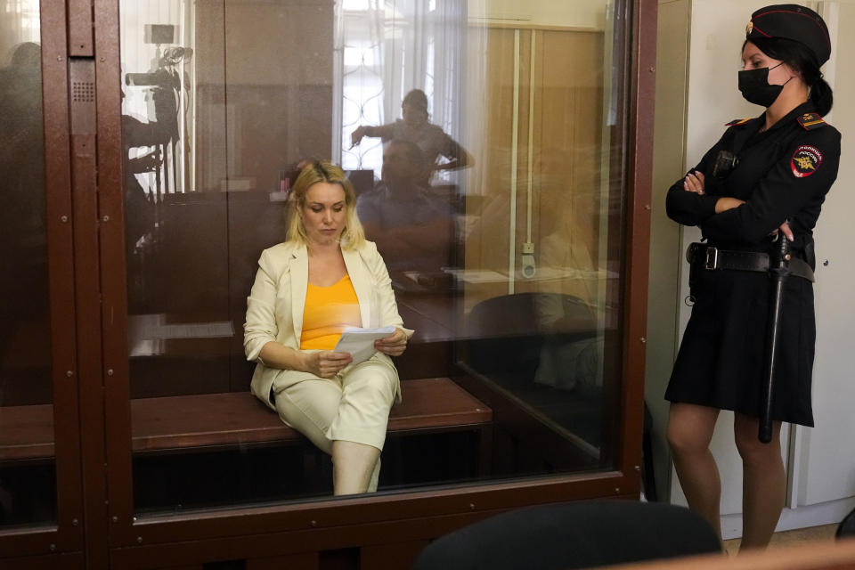 FILE - Marina Ovsyannikova, a former Russian state TV journalist who quit after making an on-air protest of Russia's military operation in Ukraine, reads a paper sitting in a court room during a hearing in Moscow, Russia, on Aug. 11, 2022. A court in Moscow on Wednesday, Oct. 4, 2023, handed a former state TV journalist a 8 1/2-year prison term in absentia for protesting Russia's war in Ukraine, the latest in a months-long crackdown against dissent that has intensified since Moscow's invasion 20 months ago. (AP Photo/Alexander Zemlianichenko, File)