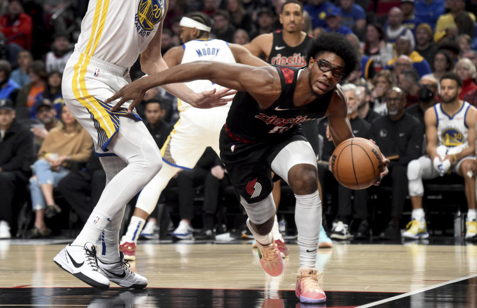 Portland Trail Blazers guard Scoot Henderson, right, dribbles past Golden State Warriors forward Dario Saric, left, during the first half of an NBA basketball game in Portland, Ore., Sunday, Dec. 17, 2023. (AP Photo/Steve Dykes)