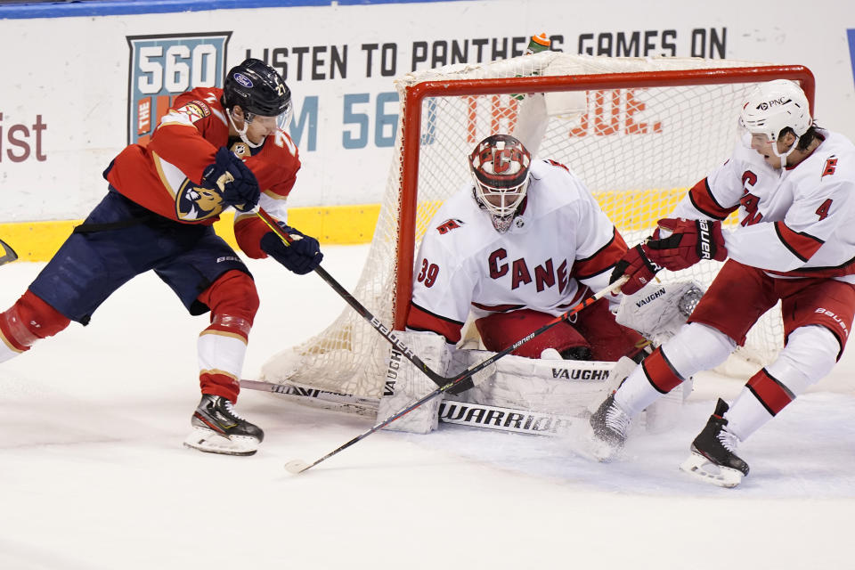 Florida Panthers center Eetu Luostarinen (27) takes a shot against Carolina Hurricanes goaltender Alex Nedeljkovic (39) and defenseman Haydn Fleury (4) during the third period of an NHL hockey game, Monday, March 1, 2021, in Sunrise, Fla. (AP Photo/Wilfredo Lee)