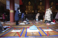 Social distancing signs are seen on the floor as parents pray during a special service to wish for their children's success in the upcoming college entrance exam on Thursday, Dec. 3, at the Jogye Temple in Seoul, South Korea, Sunday, Nov. 29, 2020. South Korea is shutting down indoor gyms offering intense workout classes and banning year-end parties at hotels in the greater Seoul area to fight the virus. Prime Minister Chung Sye-kyun said Sunday. The signs read: "Please empty this place." (AP Photo/Ahn Young-joon)