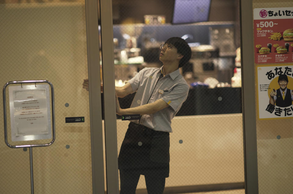 A staff member at a McDonald's store shuts the door of the shop as it closes earlier than usual citing a system failure, in Tokyo, Friday, March 15, 2024. (AP Photo/Hiro Komae)