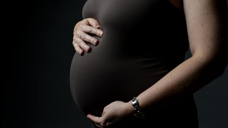 A pregnant woman cradles her stomach.