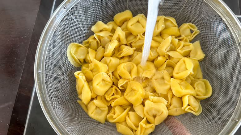 water streaming over tortellini in colander