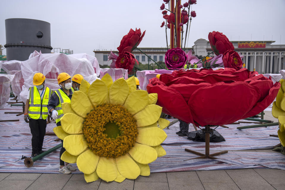 FILE - In this Sept. 18, 2021, file photo, workers move a giant flower blossom as part of preparations for China's National Day holiday on Tiananmen Square in Beijing. China's "zero tolerance" strategy of trying to isolate every case and stop transmission of the coronavirus has kept kept the country where the virus first was detected in late 2019 largely free of the disease. (AP Photo/Mark Schiefelbein, File)