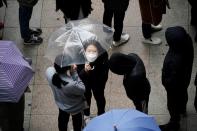 People wearing masks after the coronavirus outbreak wait in a line to buy masks as it rains in front of a department store in Seoul