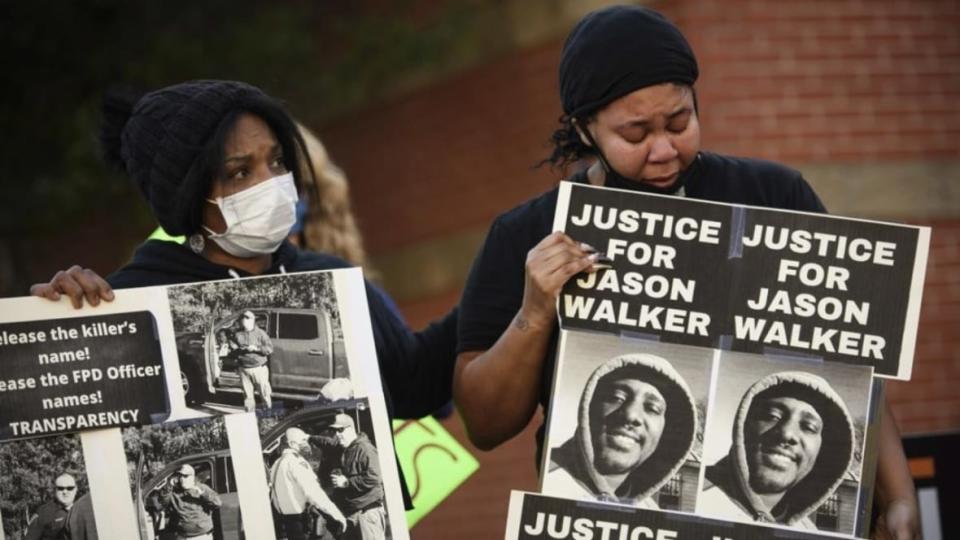 Pandora Harrington (right) cries and is comforted as she holds a sign with an image of Jason Walker during a demonstration in front of the Fayetteville Police Department on Jan. 9, 2022, in North Carolina. Walker was shot and killed by an off-duty sheriff’s deputy in Fayetteville. (Photo: Andrew Craft/The Fayetteville Observer via AP, File)