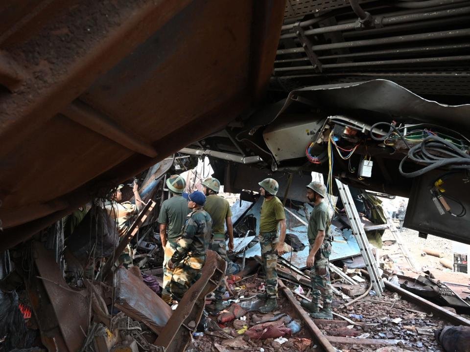 Military personnel search for survivors amid wreckage at the accident site.