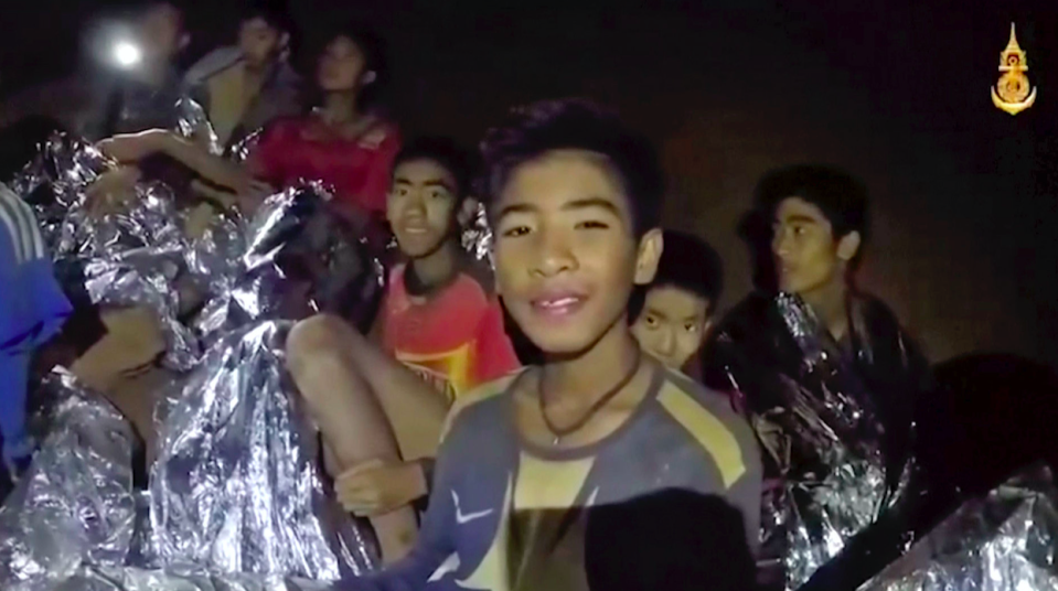 <em>Thai boys smile as Thai Navy SEAL medics help injured children inside the cave in Mae Sai (AP)</em>