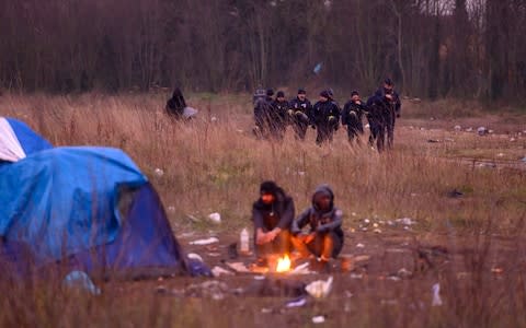 Two men keep warm by a fire as police patrol - Credit: Paul Grover