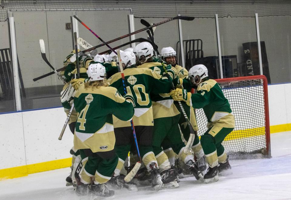 St. Mary Catholic Central hockey players pile on their goalie Tuesday night to celebrate their first win in three years. The Falcons beat Huron United 5-4.