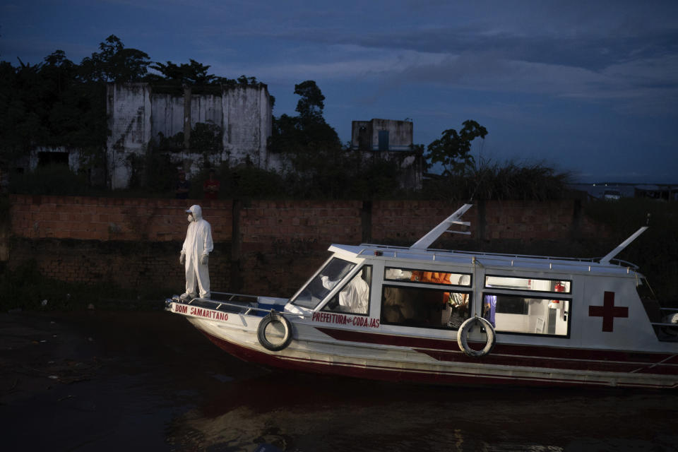 A health worker stands on a boat carrying COVID-19 patient Jose da Conceição as he waits for an ambulance to transfer him to a hospital after arriving in the port of Manacapuru, Amazonas state, Brazil, Monday, June 1, 2020. (AP Photo/Felipe Dana)