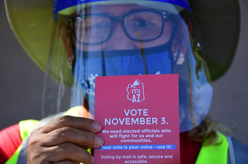 A Democratic Party canvasser holds up campaign material while knocking on doors in the suburbs of Phoenix on Oct. 15, 2020, to encourage people to vote in the presidential and congressional elections.