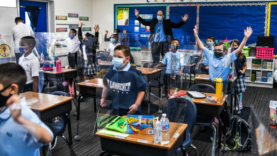 The new Superintendent of Schools for the Archdiocese of Miami, Jim Rigg (back of class), dances with students wearing masks on the first day in school at the St. Lawrence Catholic School, on Aug. 18, 2021.