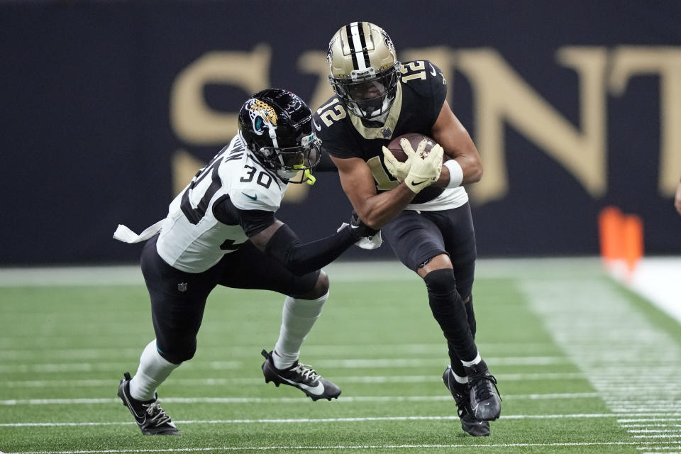 New Orleans Saints wide receiver Chris Olave (12) runs for a first down before he is tackled by Jacksonville Jaguars cornerback Montaric Brown (30) in the first half of an NFL football game in New Orleans, Thursday, Oct. 19, 2023. (AP Photo/Gerald Herbert)