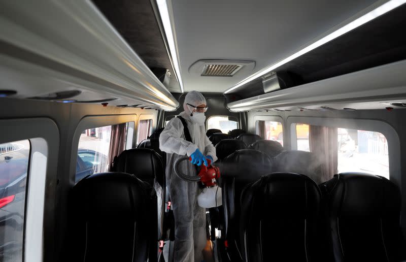 A Palestinian worker in a protective suit disinfects a bus as a preventive measure against the coronavirus in Beit Jala town in the Israeli-occupied West Bank