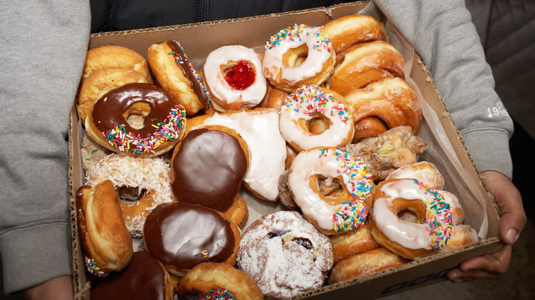 A person with a box of assorted donuts
