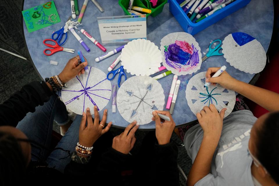 As part of the Columbus Metropolitan Library's Winter Reading Challenge program, (right to left) Savayah Singletary, 10, Fiona Clarke, 14, and Aicha Sow, 13, create snowflakes and holiday messages out of a coffee filter and craft supplies Dec. 15 at the library system's Reynoldsburg branch.