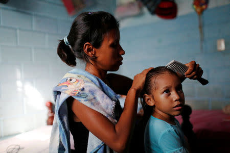 Alejandra Jordan, 30, combs her daughter Valeria's hair at their home in San Francisco de Yare, Venezuela July 11, 2016. REUTERS/Carlos Garcia Rawlins