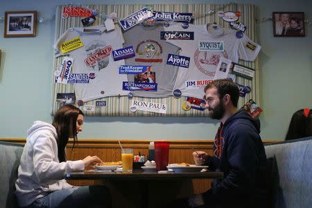 Chantal Roy (L) and Robert Desmarais sit down for breakfast under a collage of political campaign stickers at Chez Vachon in Manchester, New Hampshire December 17, 2014. REUTERS/Brian Snyder