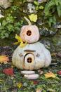 <p>Little hands will love helping create and keeping and eye out for the gnomes that are surely going to move into this sweet little gourd cottage. To display, try setting on a table on a soft bed of moss.</p><p><strong>To make:</strong> Cut a hole in the bottom of a medium blue Hubbard squash; scoop out the pulp and seeds. Cut out the door and circular door window. Etch lines in the door with a linoleum carving tool and insert toothpicks (shortened if necessary) to create window muttons. Lightly draw flower design on either side of door with a pencil and use linoleum carving tool to etch out. Insert the door into the opening and hold in place with toothpicks. Hot glue mini glass balls into acorn caps to create lights; attach to pumpkin with hot glue. Cut half to 2/3 off of a wood round; attach to pumpkin, above the door, to create an awning.</p><p>Cut a hole in the bottom of a small brown or green acorn squash; scoop out the pulp and seeds. Cut a circular window and insert toothpicks (shortened if necessary) to create window muntins. Lightly draw flower design around window with a pencil and use linoleum carving tool to etch out. Stack pumpkins and add wood round steps and gingko leaves.</p>