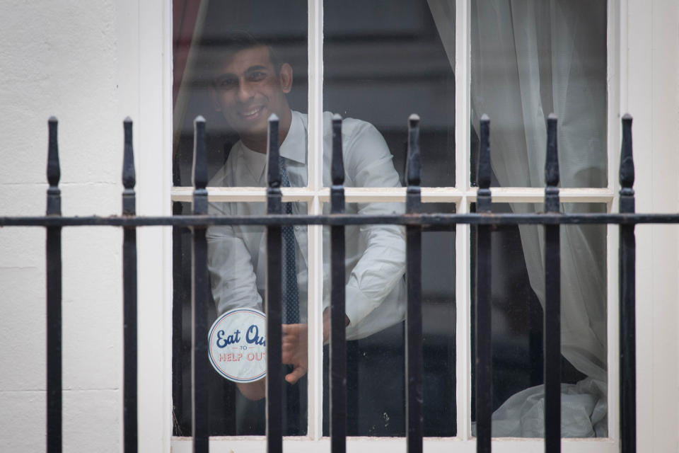 Chancellor Rishi Sunak places an 'Eat out to help out' sticker in the window of No.11 Downing Street in London, ahead of the new scheme encouraging customers to return to the hospitality industry. The initiative will provide up to £10 off meals to diners eating out every Monday, Tuesday and Wednesday during August at participating businesses across the UK. PA Photo. Picture date: Thursday July 16, 2020. See PA story HEALTH Coronavirus. Photo credit should read: Stefan Rousseau/PA Wire