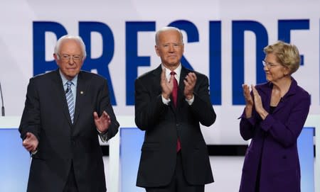 Democratic presidential candidates Sen. Sanders, former Vice President Biden and Sen. Warren applaud as they pose together at the start of the fourth U.S. Democratic presidential candidates 2020 election debate in Westerville, Ohio