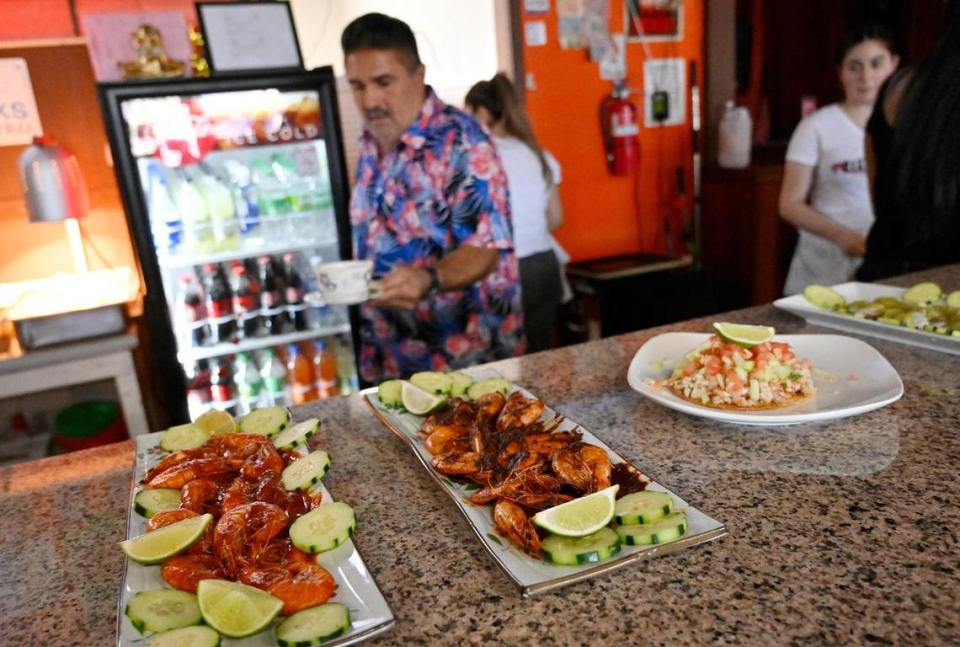 Raul Godinez places samples of the food served at El Godinazo Fresno Centro Botanero including prawns and ceviche Friday, June 23, 2023. ERIC PAUL ZAMORA/ezamora@fresnobee.com
