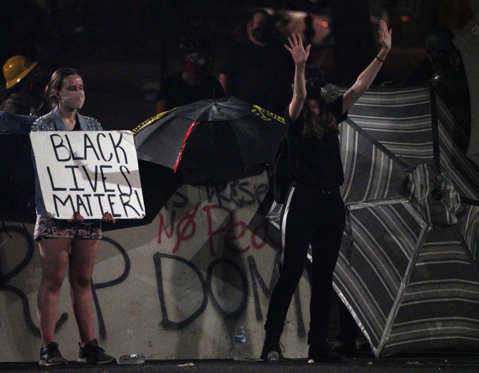 Two people protest silently outside the Mark O. Hatfield Federal Courthouse in Portland, Oregon, on Monday night.