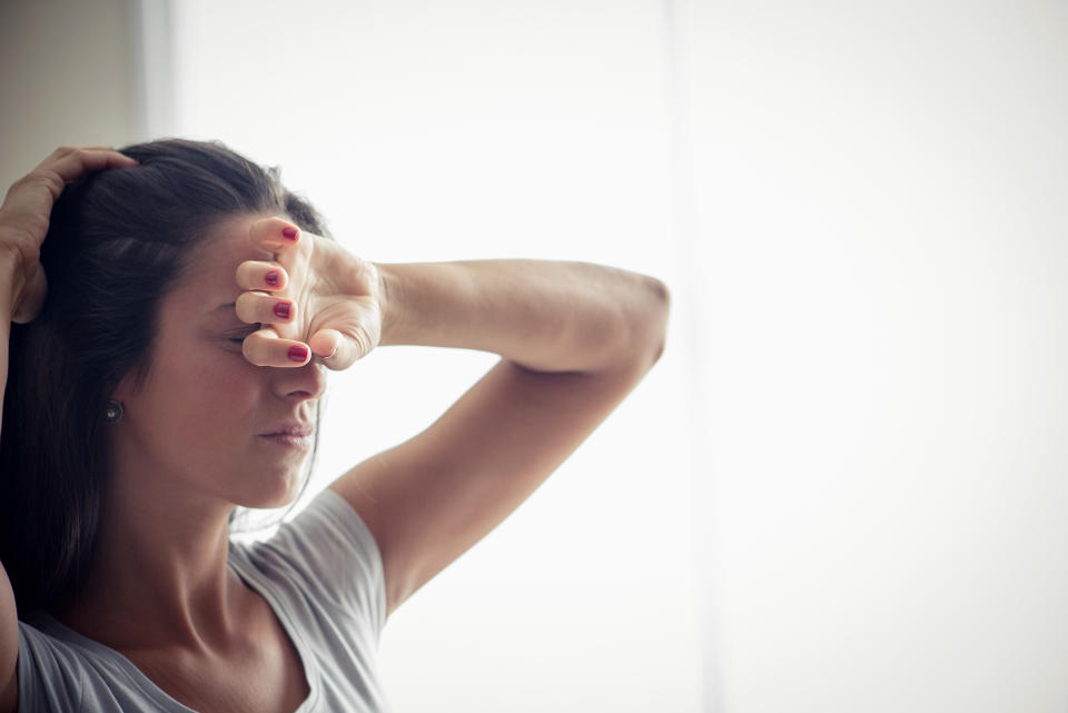 Young woman holding one hand on forehead