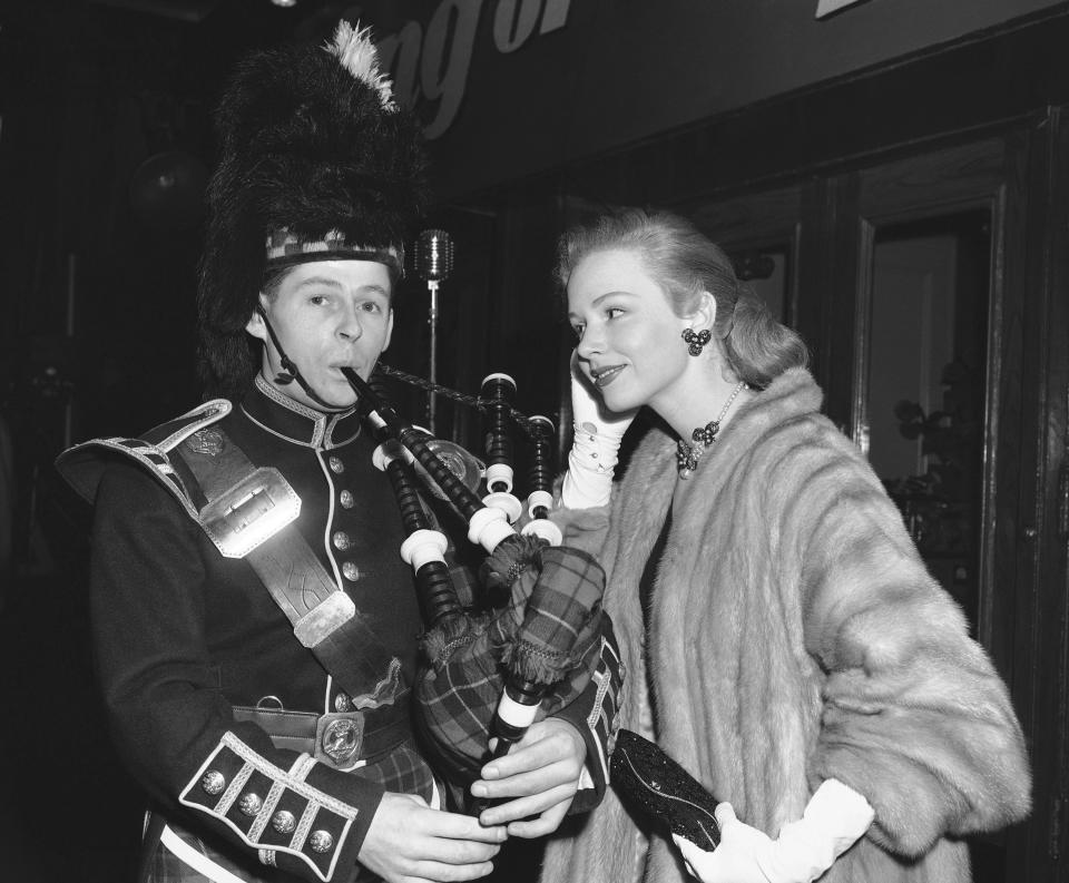 FILE - Actress Piper Laurie watches piper Thomas Gorrian of the Lovat Pipe Band as he pipes a tune before the gala world premiere of a 3-D film, "King of the Khyber Rifles," at the Rivoli Theater in New York, Dec. 23, 1953. Laurie, the strong-willed, Oscar-nominated actor who performed in acclaimed roles despite at one point abandoning acting altogether in search of a “more meaningful” life, died early Saturday, Oct. 14, 2023, at her home in Los Angeles. She was 91. (AP Photo/Ed Ford, File)