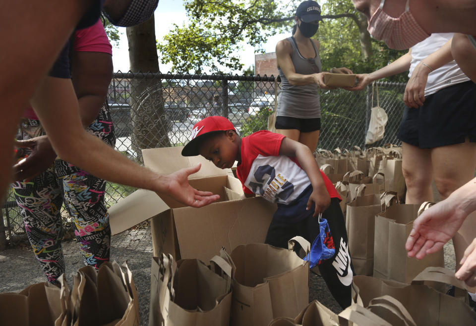 Hunter Stewart, 5, helps pack and deliver food to residents of the Lafayette Gardens housing development on Saturday, Aug. 8, 2020, in the Brooklyn borough of New York. Stewart currently lives in a shelter for families with his mother. After he and his family struggled to put food on the table in the first months of the pandemic, they volunteered to help distribute supplies to neighbors who also were having difficulty staving off hunger. (AP Photo/Jessie Wardarski)