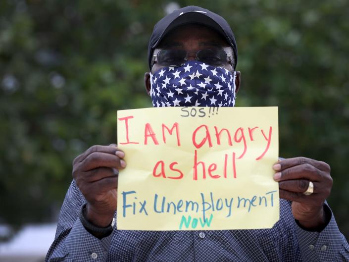 an unemployed worker holds a sign that says  I Am angry as hell Fix Unemployment Now,&#39;