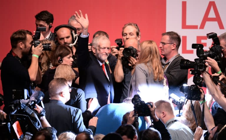 British opposition Labour Party leader Jeremy Corbyn (C) waves following his speech after being announced as the winner of the party's leadership contest at the Labour Party Leadership Conference