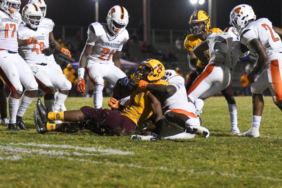 The Booker T. Washington defense brings down Glades Central running back Desmond Washington in the first half against Glades Central in a South Florida Tri-County tournament game on Friday, Dec. 4, 2020, in Belle Glade, Florida.